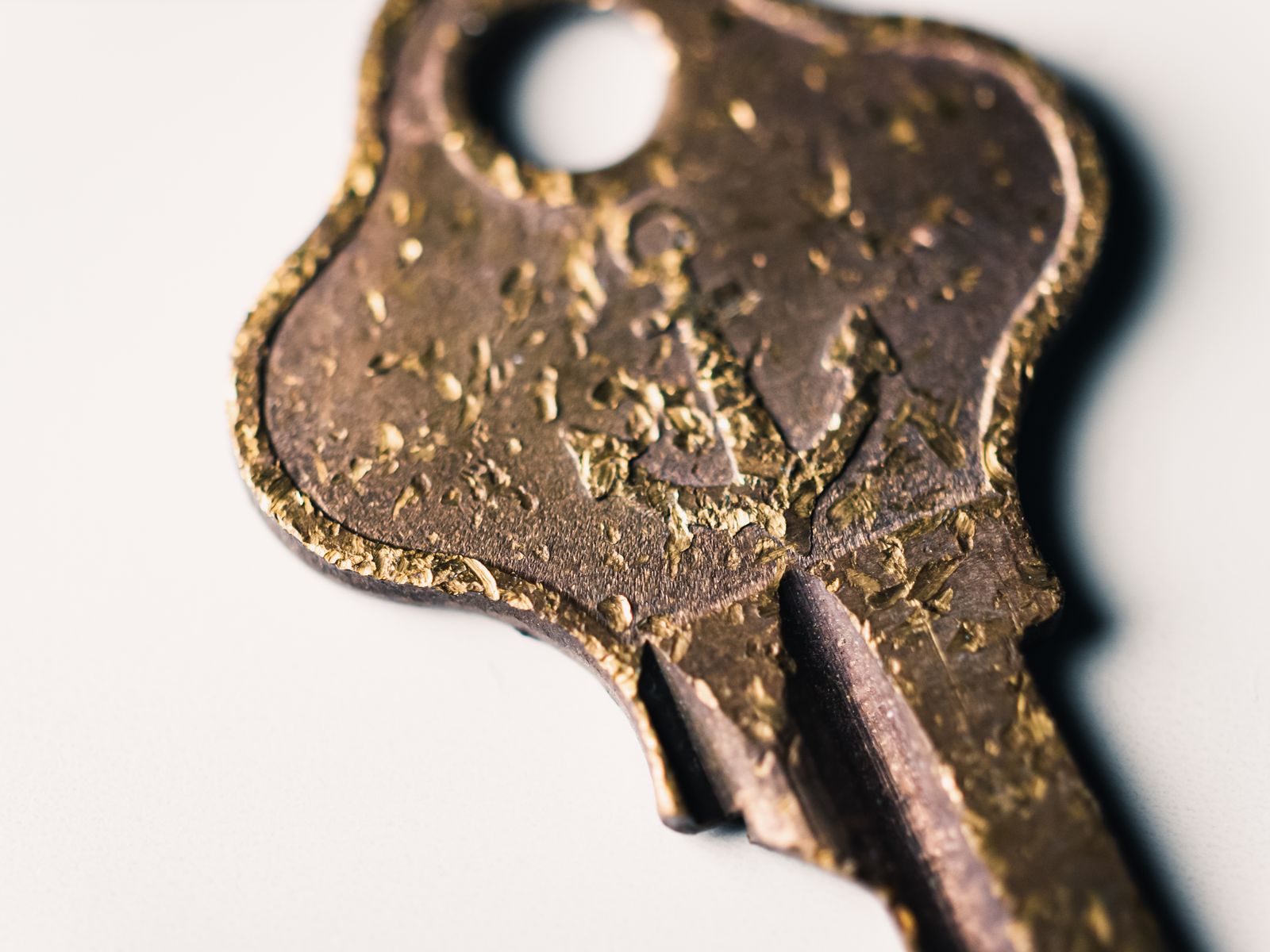 Close-up of an aged brass key lying on a plain light surface