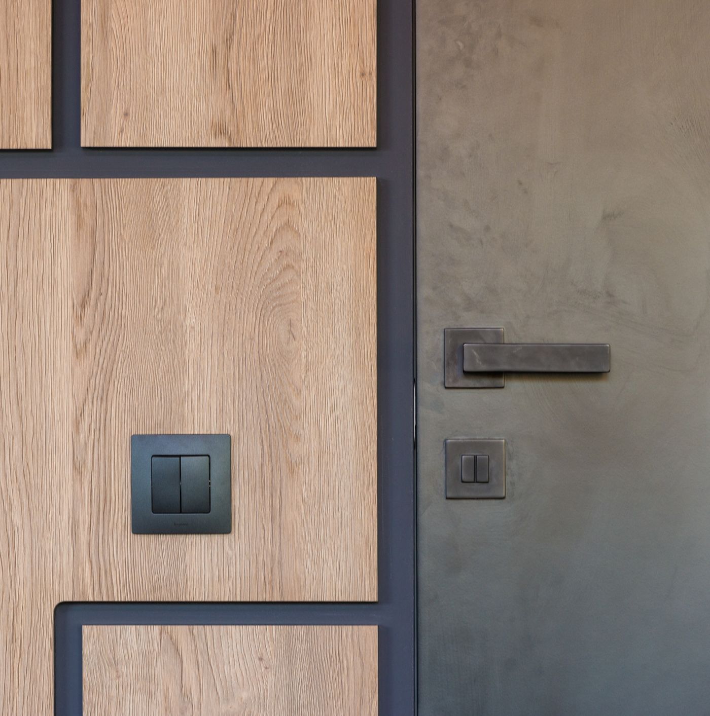 An oak-paneled wall beside a dark apartment door with a plain metal handle