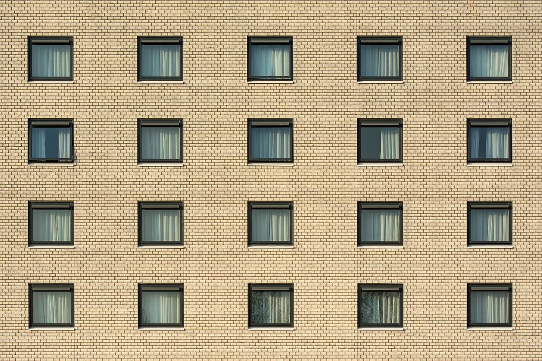 Cream brick apartment facade with a uniform grid of identical windows