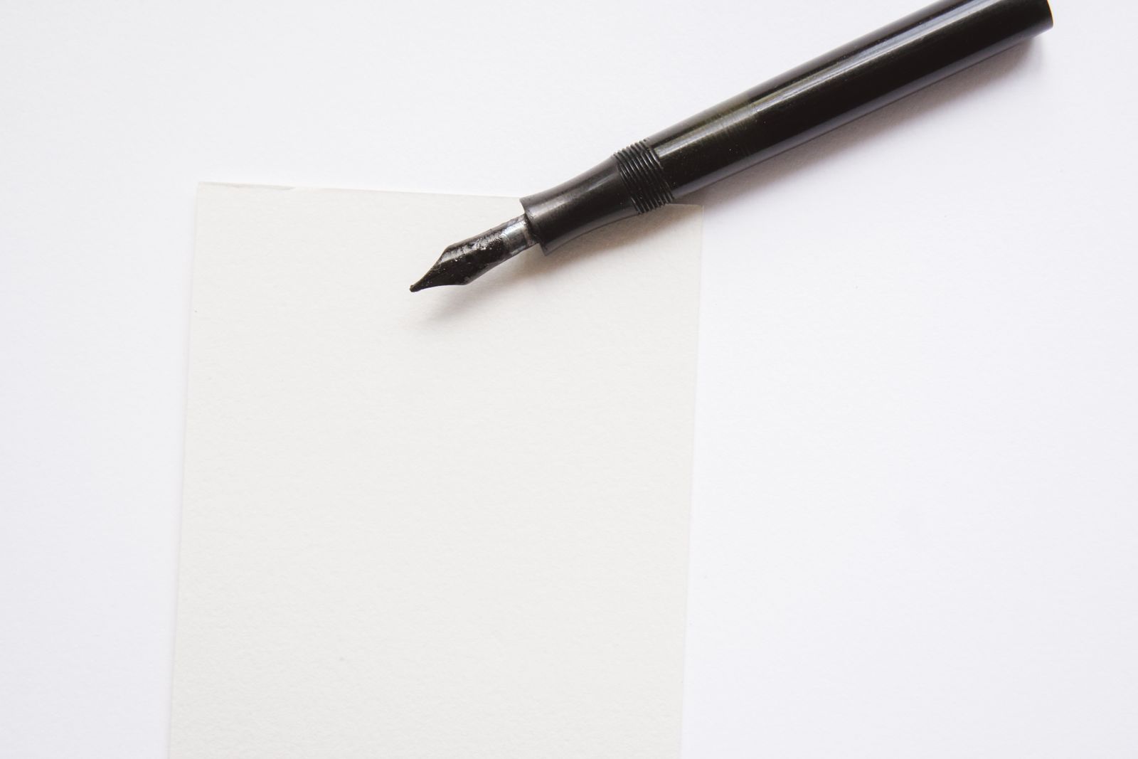 Black fountain pen resting on a blank sheet of paper