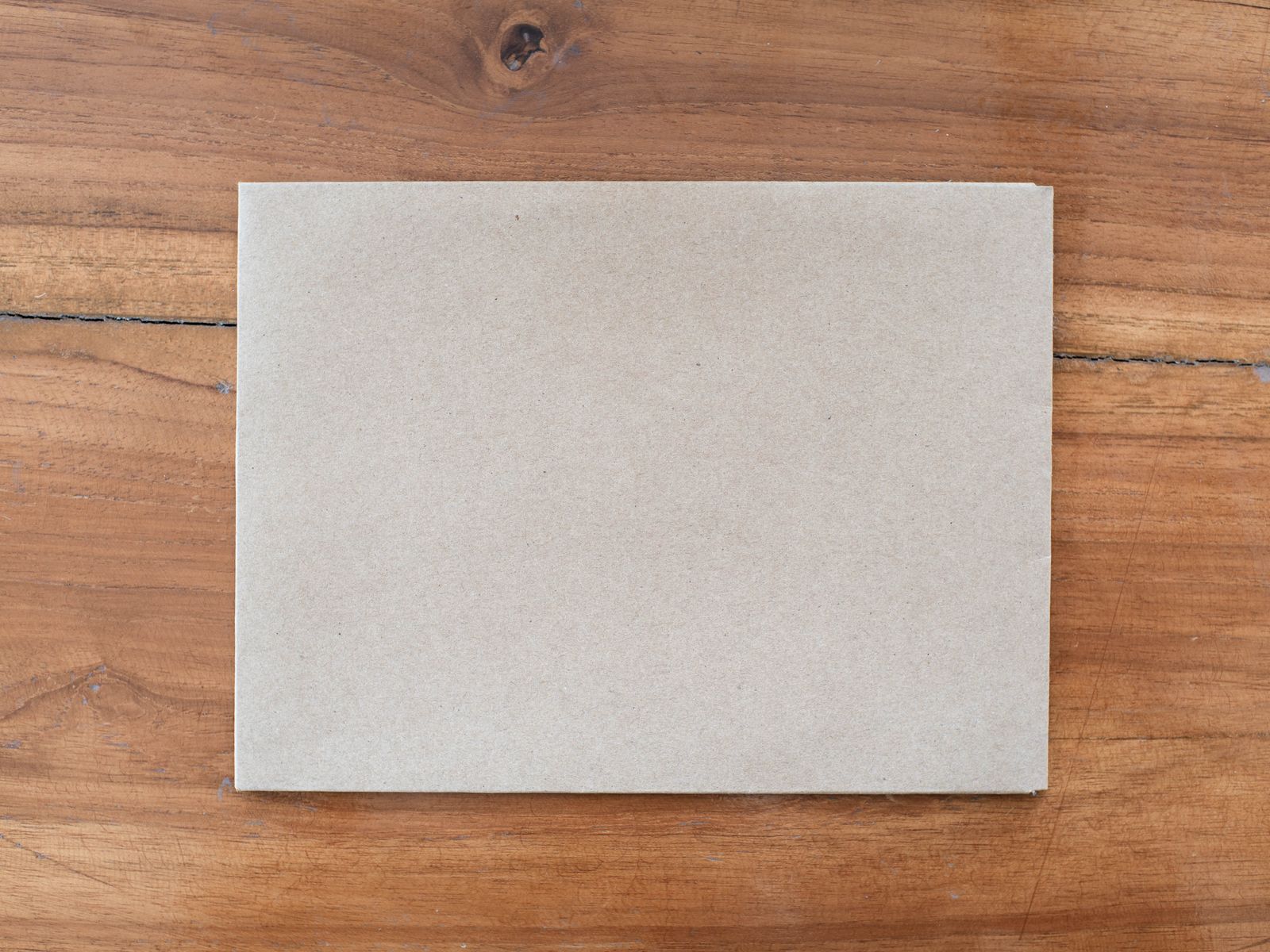 Plain kraft envelope lying closed on a wooden table
