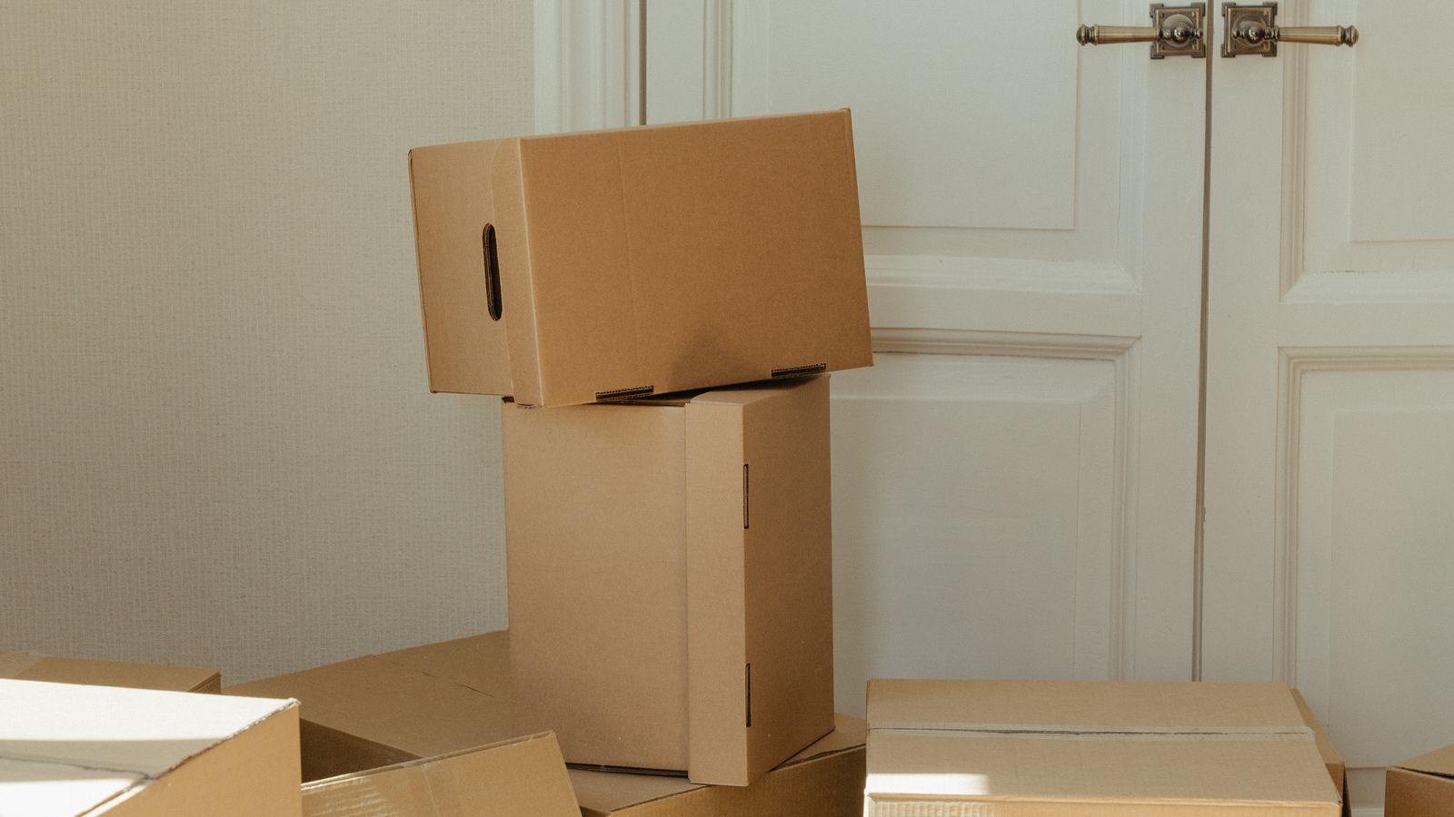 Stacked cardboard moving boxes in a bright, empty room