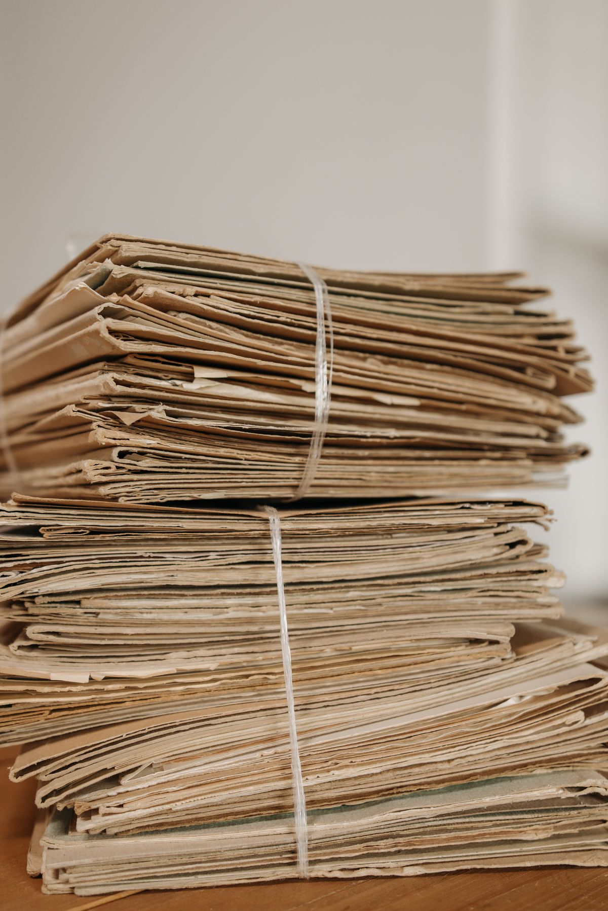 Two bundles of aged papers tied with string on a light wooden desk