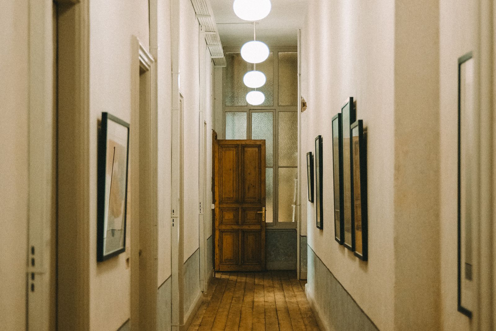 Quiet corridor of an older apartment building with a wooden door standing open at the end